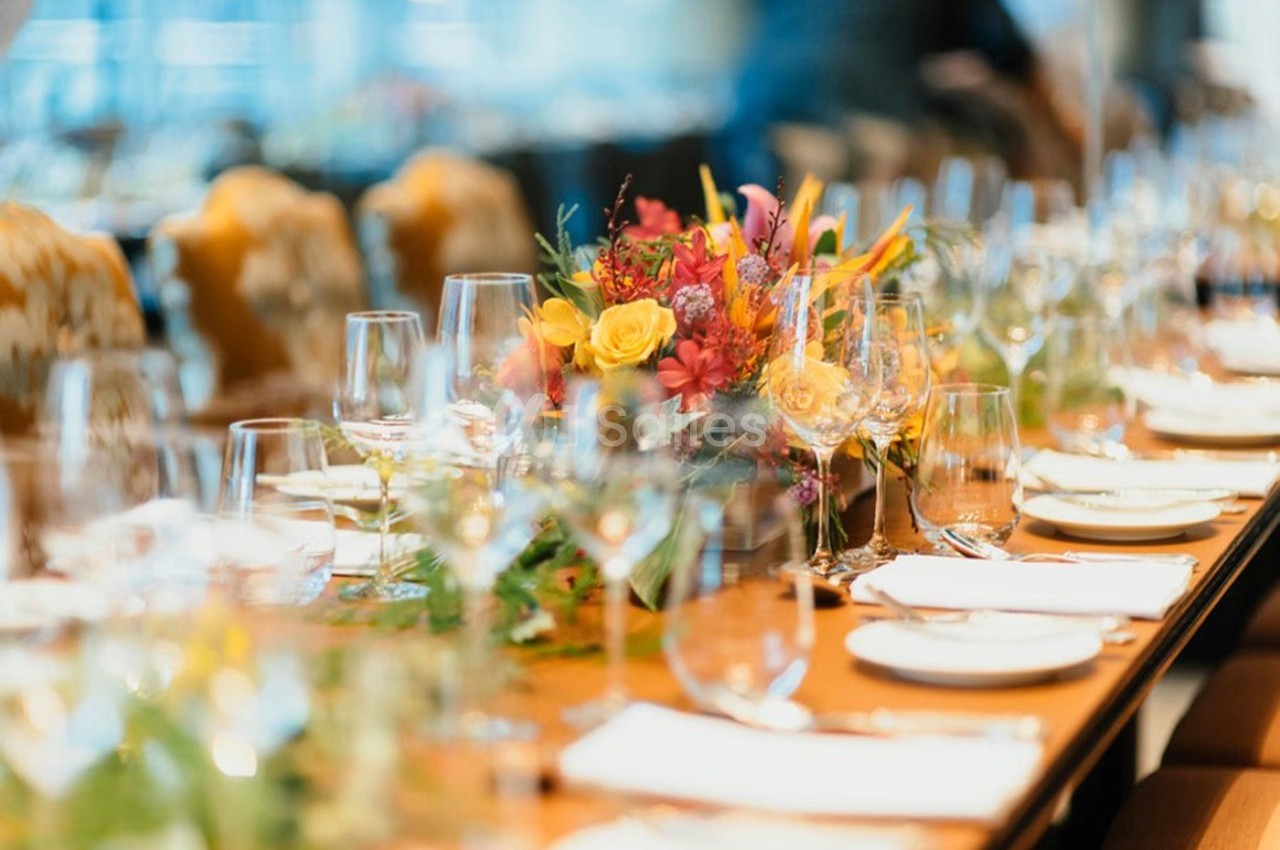 Table dressée avec des verres, des assiettes et un centre de table floral coloré dans un cadre élégant.