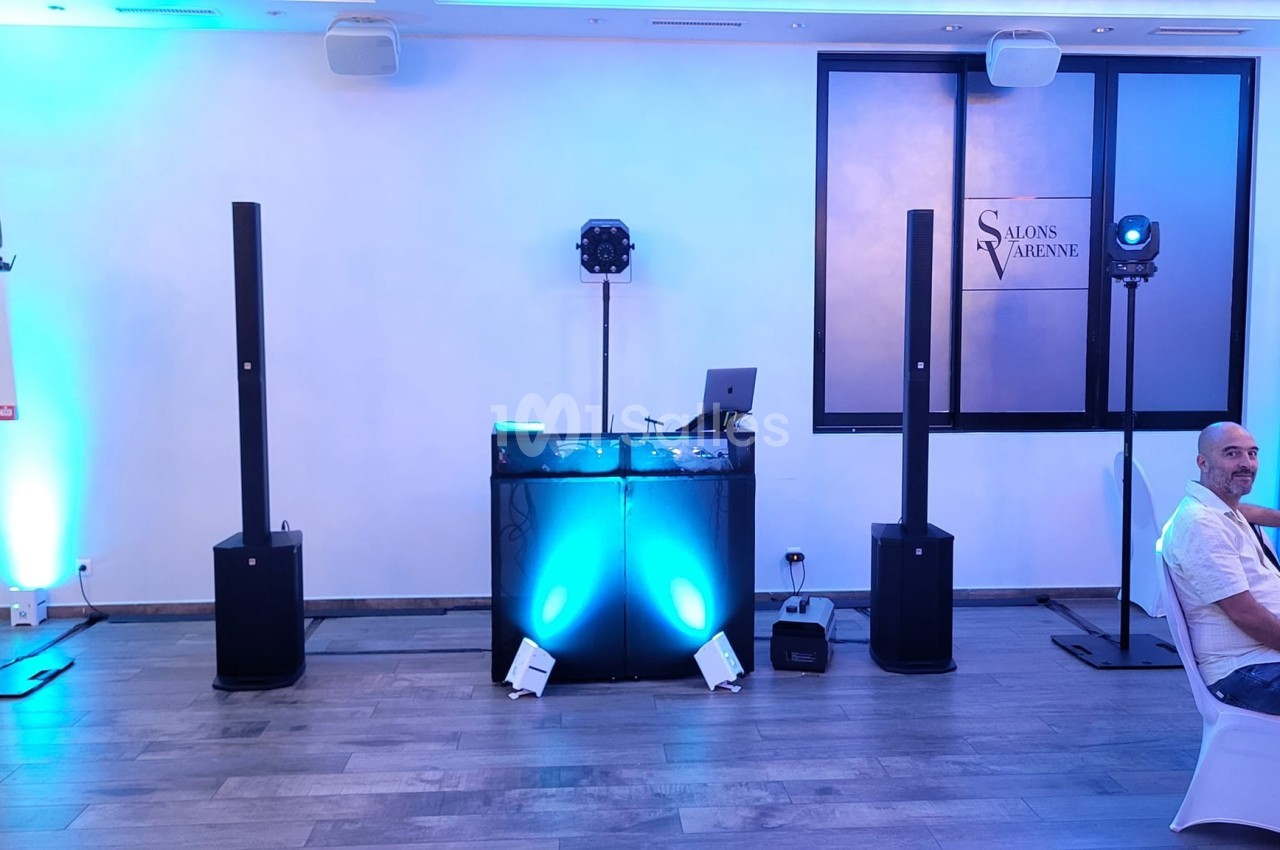 Installation de matériel de sonorisation et d'éclairage dans une salle avec un pupitre lumineux et des enceintes.