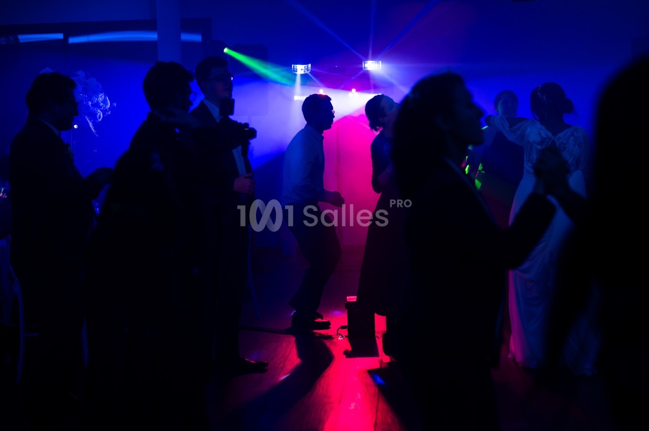 Des personnes dansent dans une salle sombre éclairée par des lumières colorées bleues et rouges.