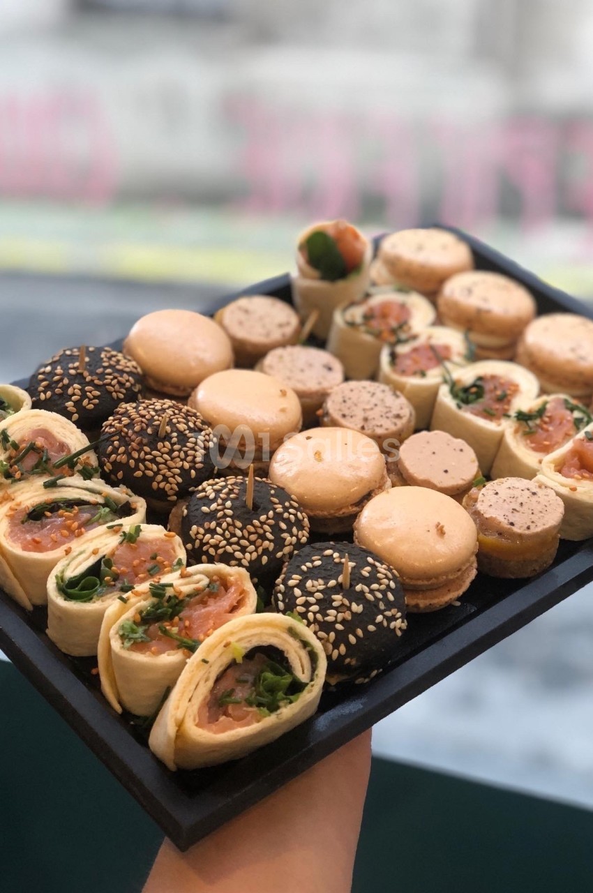 Plateau de bouchées apéritives comprenant wraps au saumon, macarons salés et mini-pains garnis.