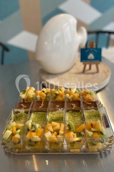 Desserts individuels composés de fruits frais et de mousse verte, présentés sur une table en métal.