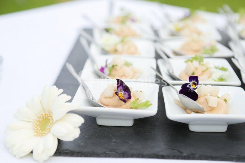 Petites assiettes de mousse garnies de fleurs comestibles et herbes, disposées sur une ardoise noire.