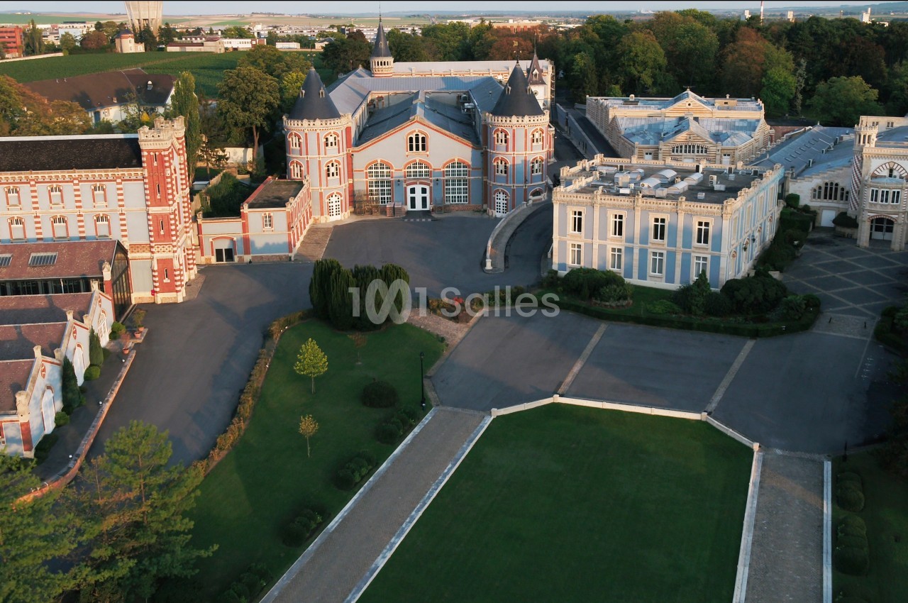 Vue aérienne d'un domaine avec plusieurs bâtiments historiques entourés de jardins et de végétation.