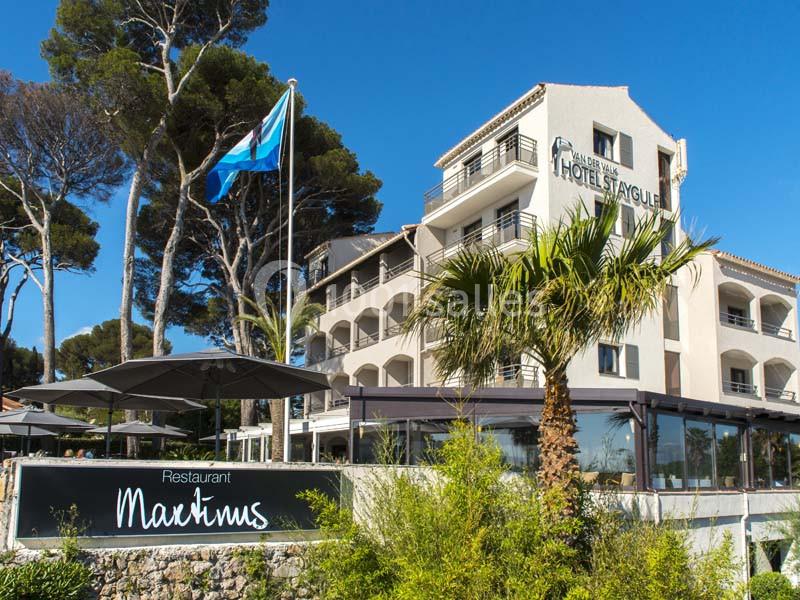 Façade d'un hôtel entouré de végétation, avec une terrasse et un panneau indiquant ’Restaurant Martinus’.