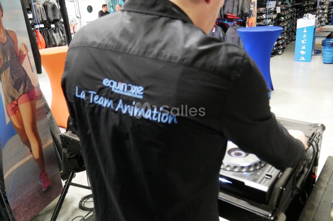 Un animateur en chemise noire utilise une table de mixage dans un magasin de sport.