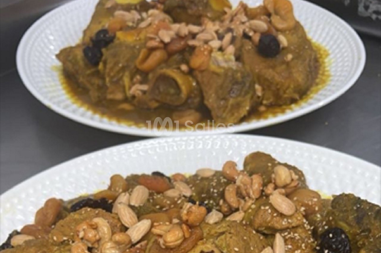 Assiette de viande mijotée garnie de fruits secs et d'amandes, présentée sur une table.