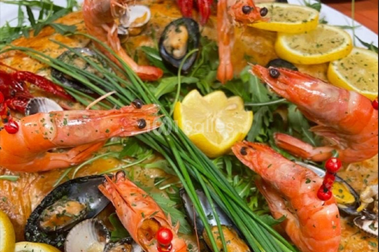 Plat de fruits de mer composé de crevettes, moules, citron, herbes fraîches et légumes sur un lit de salade.