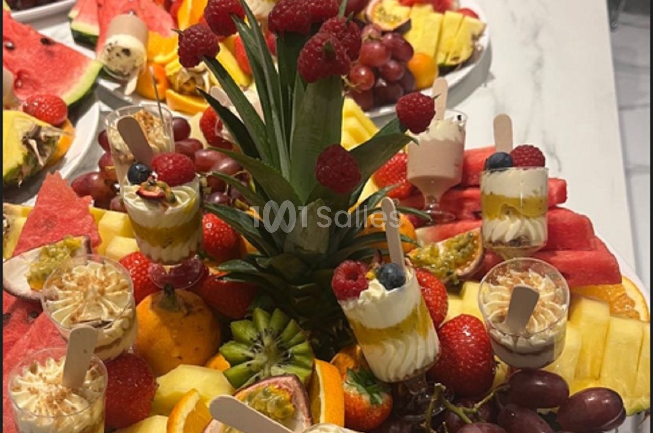 Plateau de fruits variés avec ananas, pastèque, raisins, fraises, kiwis et verrines de desserts.
