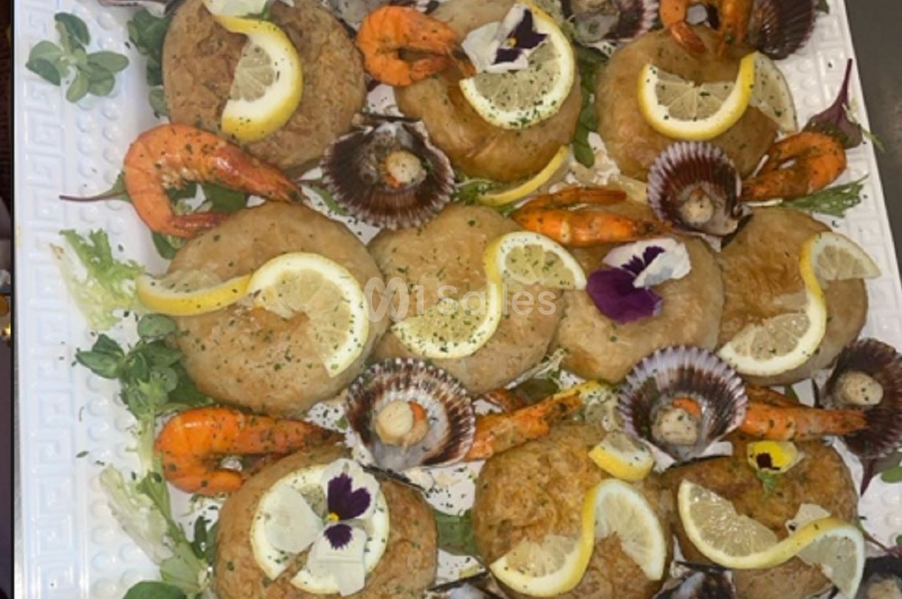 Assortiment de fruits de mer avec crevettes, coquilles Saint-Jacques et beignets garnis de citron sur un lit de salade.