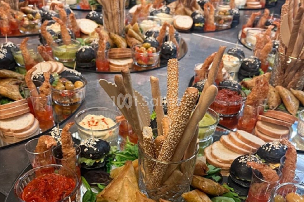 Plateaux garnis de pains, dips, légumes, feuilletés et amuse-bouches variés disposés sur une table.