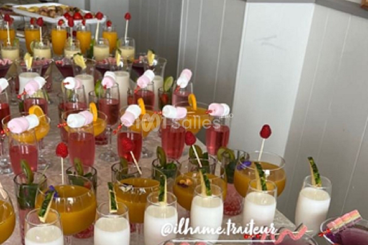 Verres de cocktails colorés garnis de fruits et décorations, disposés sur une table pour un buffet.