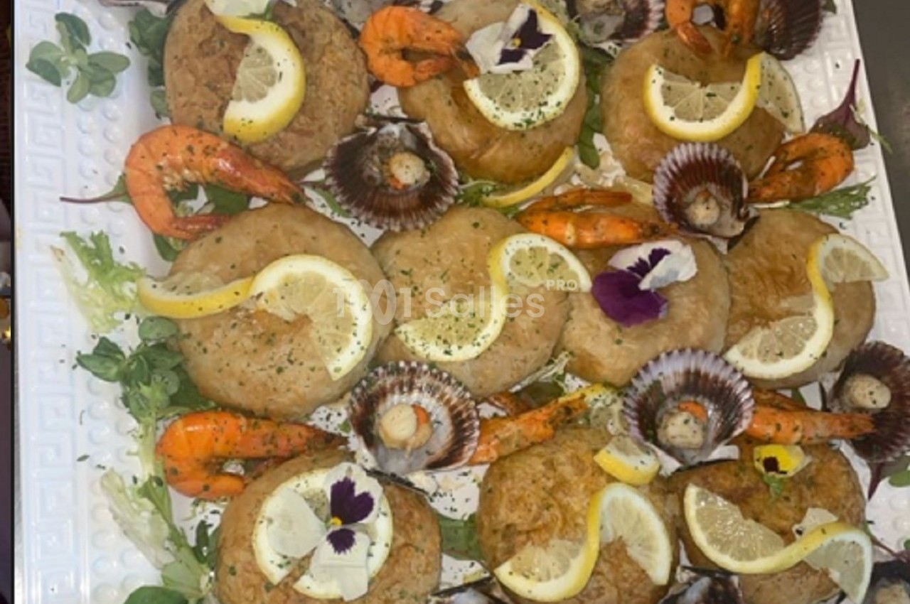 Assortiment de fruits de mer avec crevettes, coquilles Saint-Jacques et beignets garnis de citron sur un lit de salade.