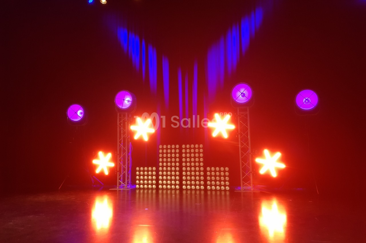 Éclairage de scène avec projecteurs rouges et bleus, étoiles lumineuses et panneaux LED sur fond sombre.