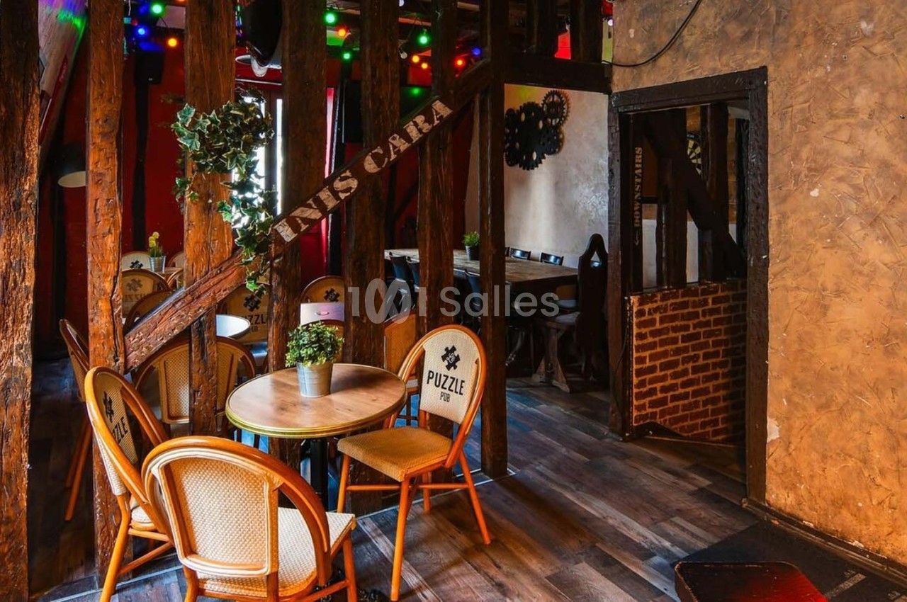 Salle de restaurant chaleureuse avec des chaises en rotin, une table ronde et une décoration lumineuse colorée.