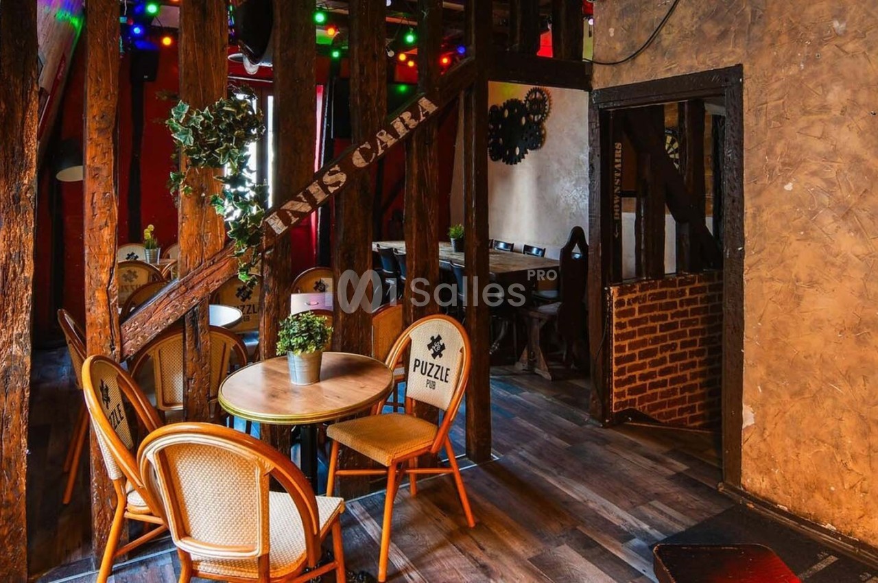 Salle de restaurant chaleureuse avec des chaises en rotin, une table ronde et une décoration lumineuse colorée.