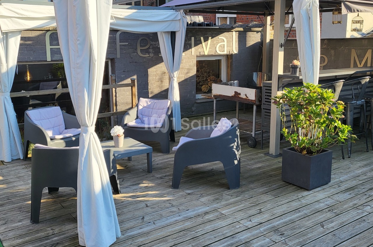 Espace extérieur avec terrasse en bois, salon de jardin sous tonnelles blanches et barbecue en arrière-plan.