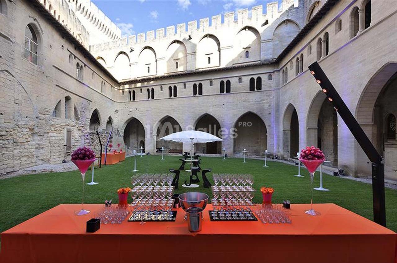 Table dressée avec verres et amuse-bouches dans une cour intérieure historique, décorée pour un événement en plein air.