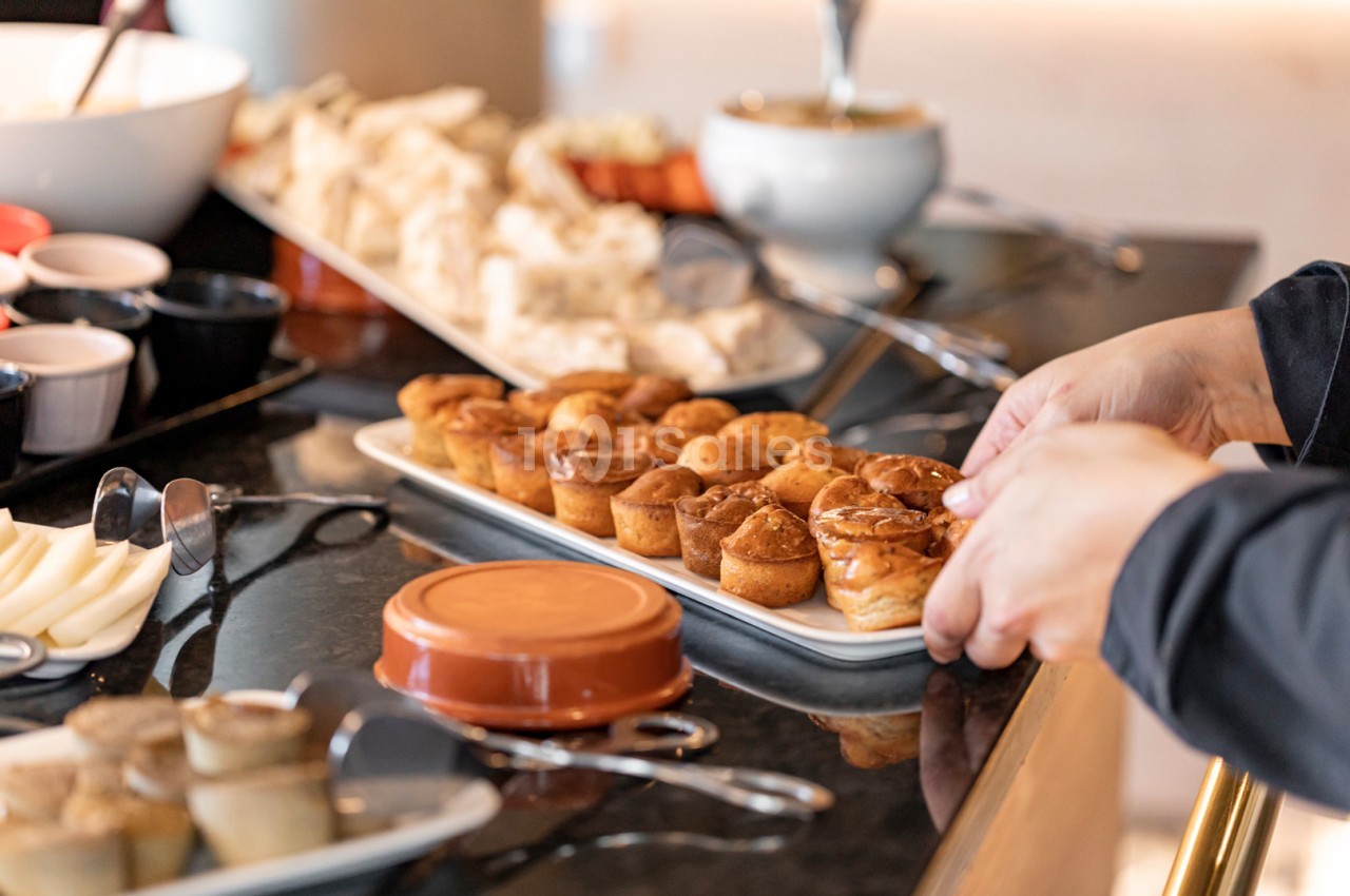 Plateau de petits gâteaux dorés disposés sur une table de buffet avec d'autres plats en arrière-plan.