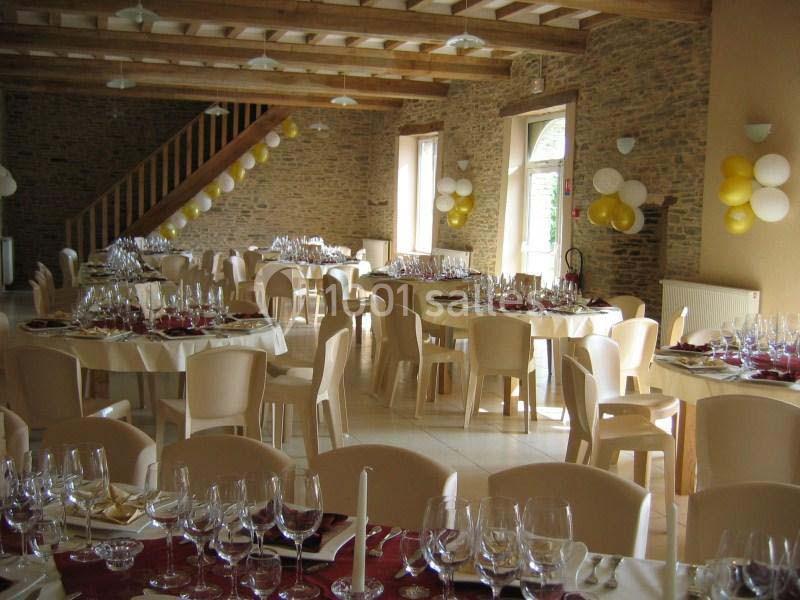 Salle de réception décorée avec des ballons et des tables dressées avec nappes rouges, verres et couverts.