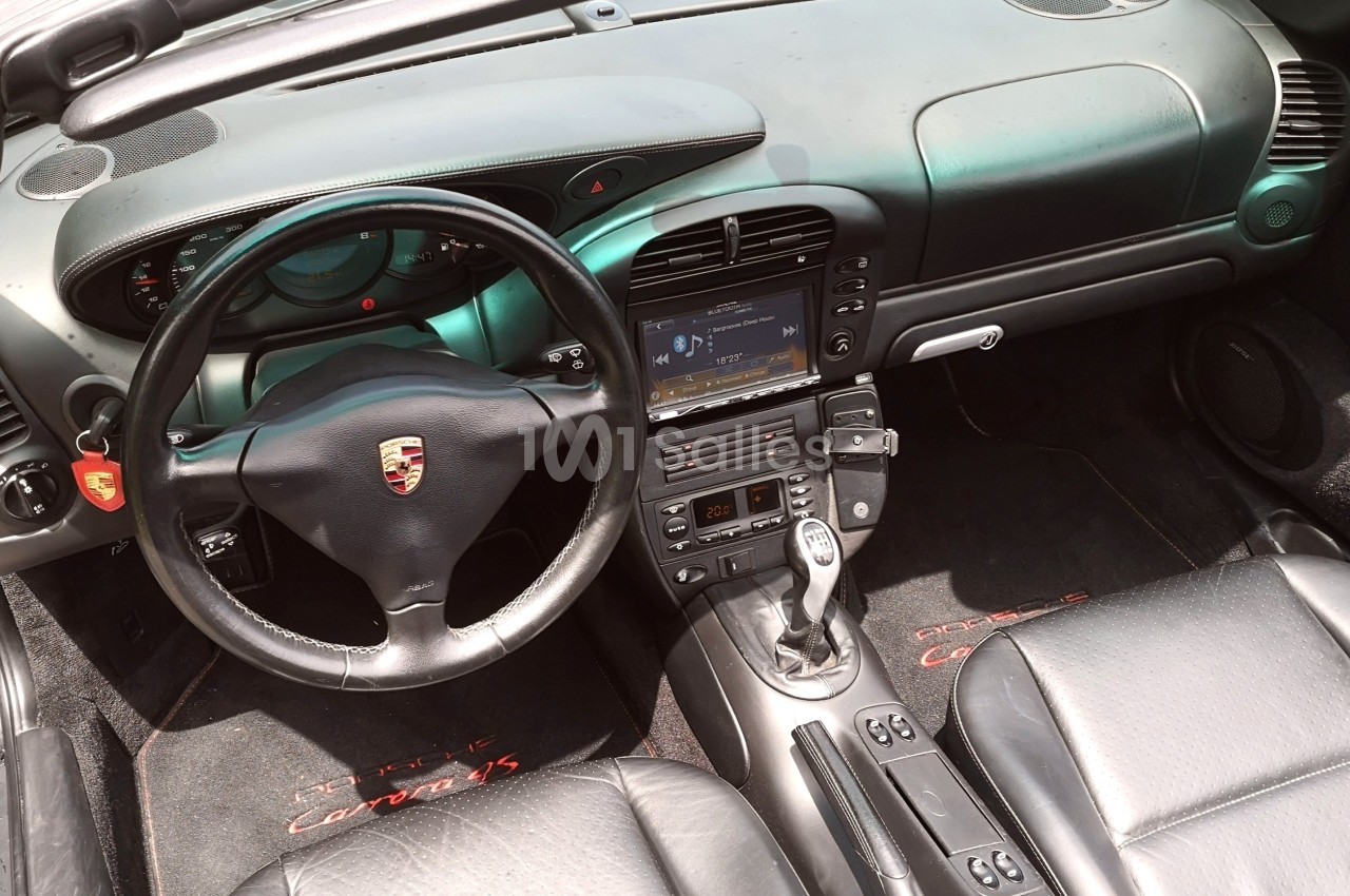 Intérieur d'une voiture avec volant, tableau de bord, écran central et sièges en cuir noir.