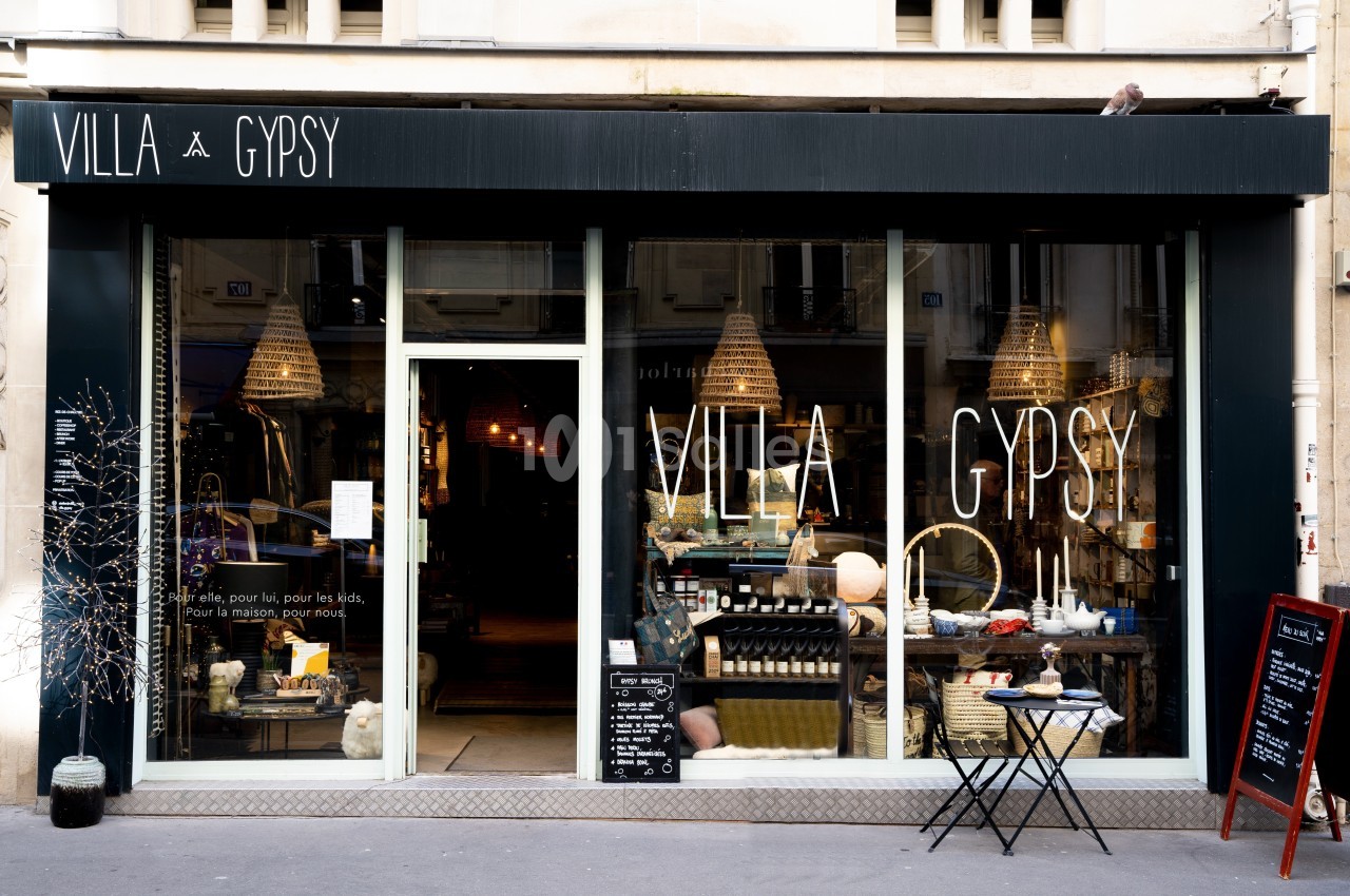 Façade d'une boutique avec une vitrine exposant des objets de décoration et un panneau noir sur le trottoir.