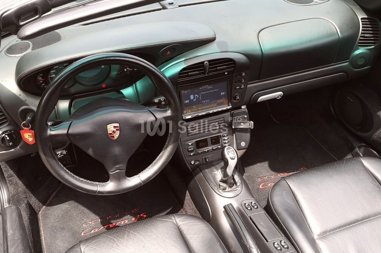 Intérieur d'une voiture avec volant, tableau de bord, écran central et sièges en cuir noir.