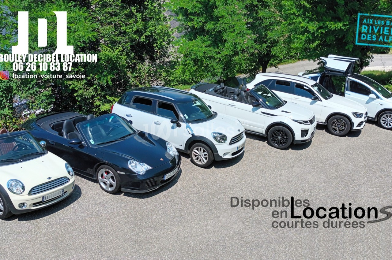 Six voitures blanches et noires alignées sur un parking, disponibles pour des locations de courte durée.