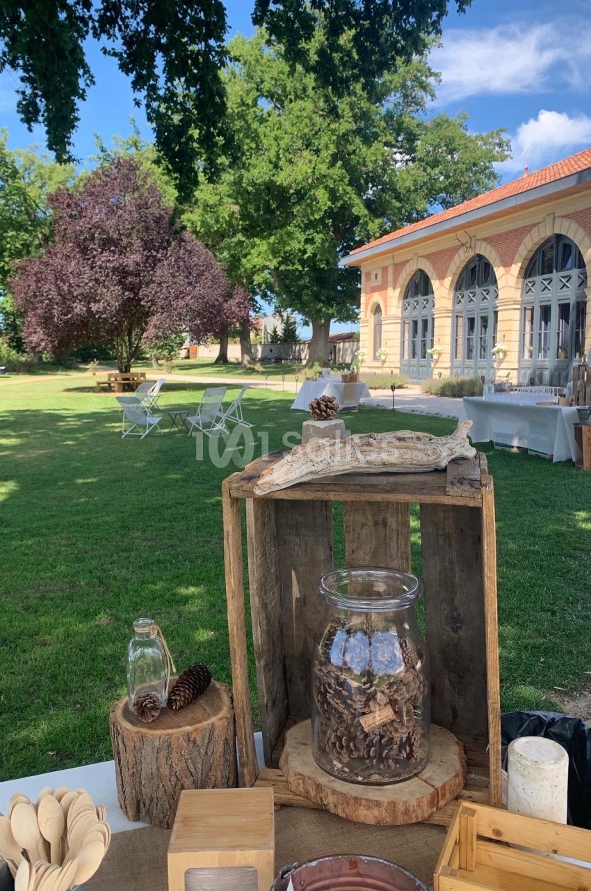 Table décorative en bois avec des éléments naturels, dans un jardin verdoyant près d'un bâtiment en briques.