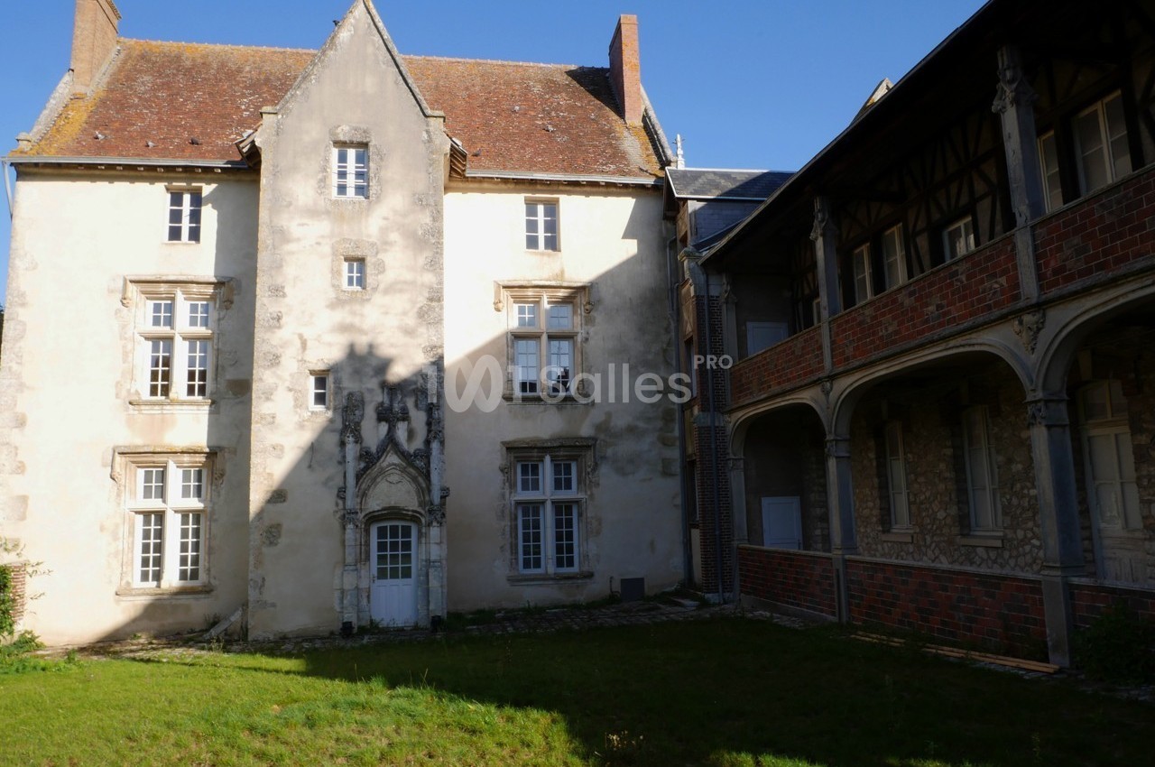 Façade d'un bâtiment ancien avec des fenêtres à croisillons, une porte sculptée et une galerie en arcades.