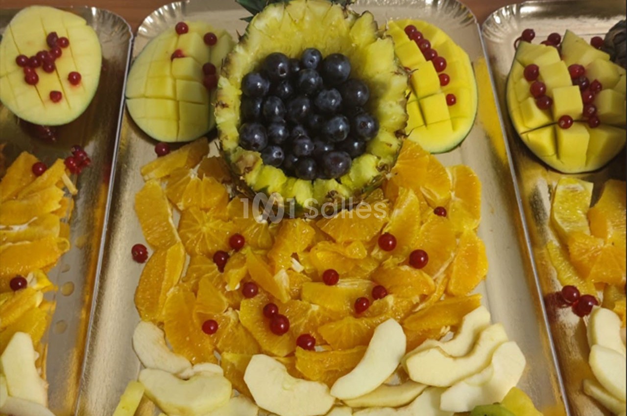 Plateaux de fruits variés avec morceaux d'orange, pomme, kiwi, mangue, groseilles et ananas garni de myrtilles.