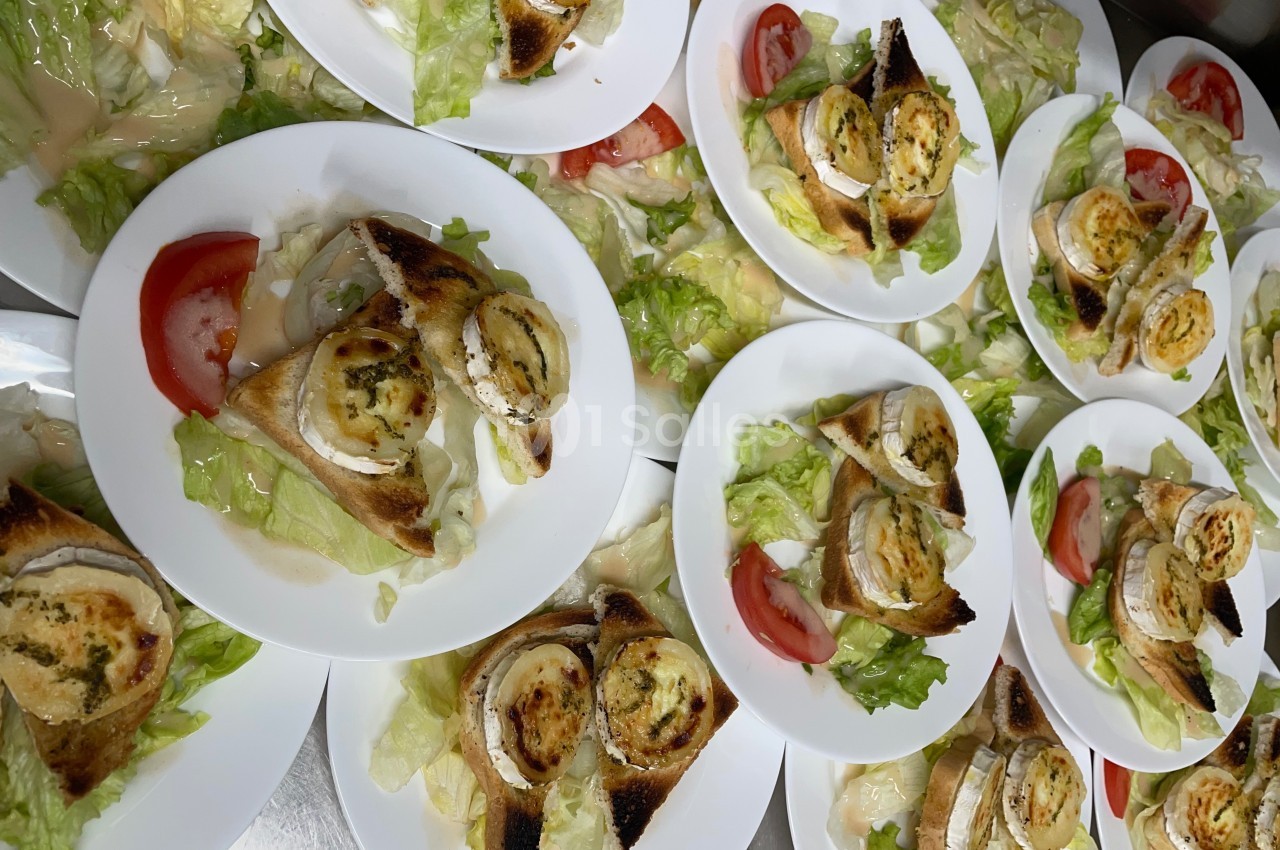 Assiettes de salade garnies de toasts au fromage de chèvre gratiné, tranches de tomate et feuilles de laitue.