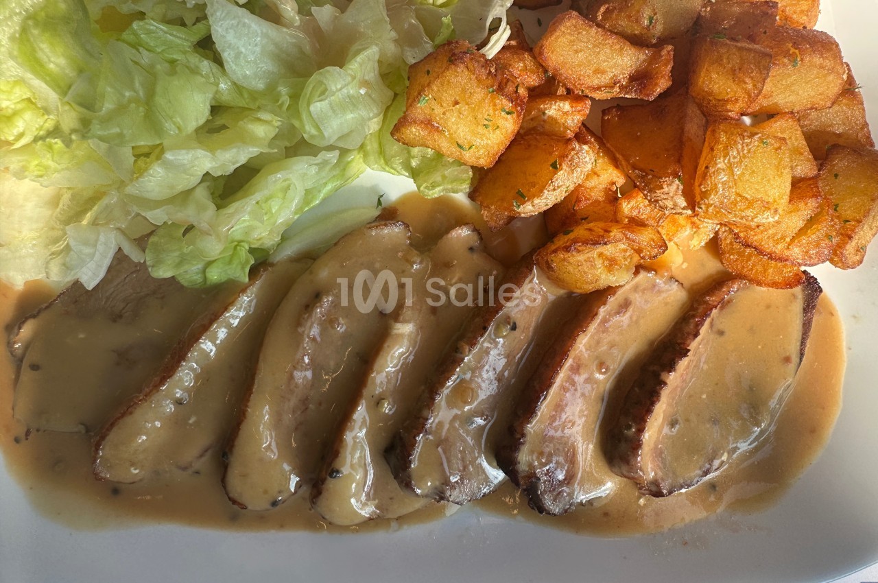 Assiette contenant des tranches de viande en sauce, accompagnées de pommes de terre rissolées et de salade verte.