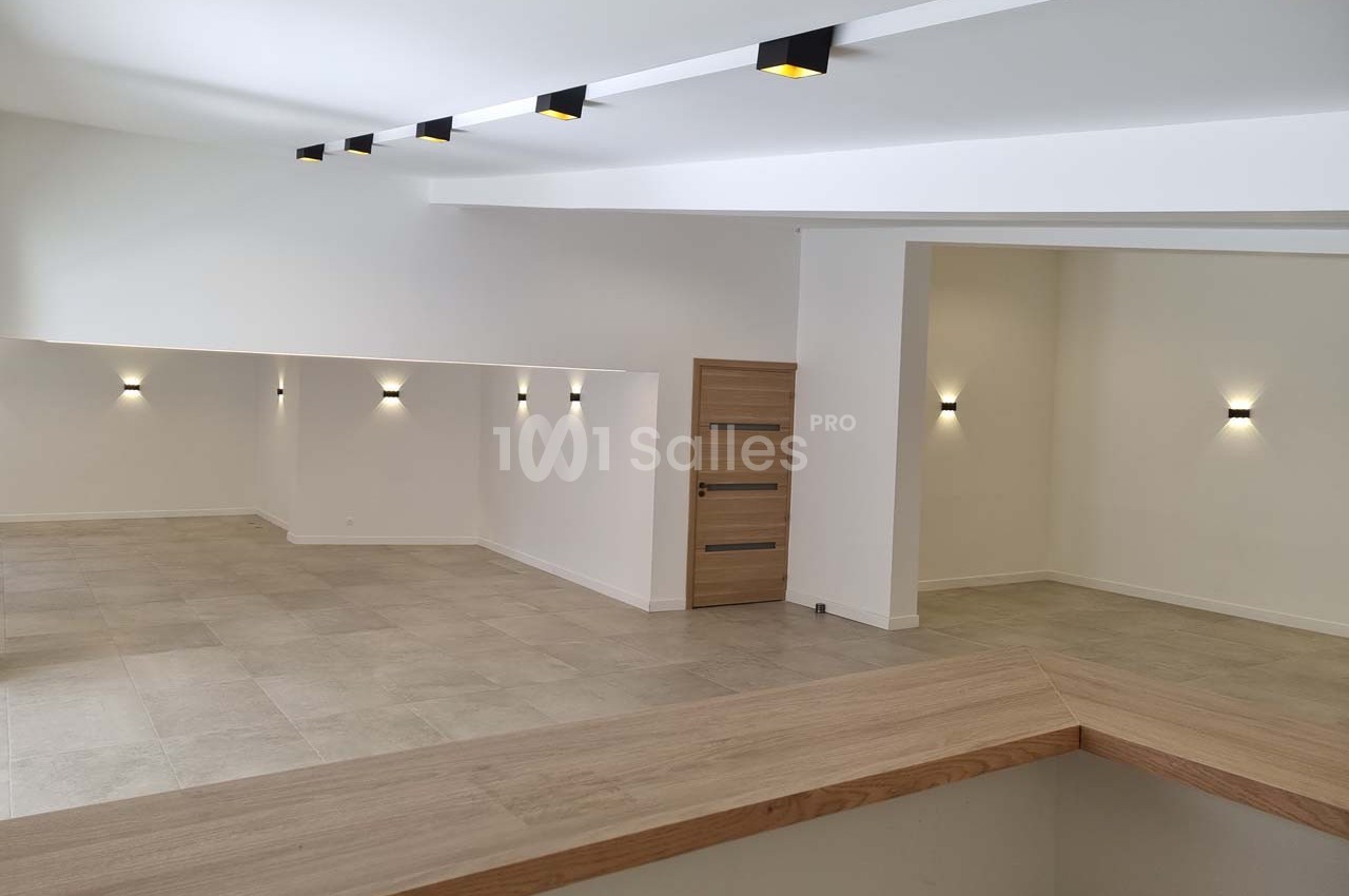 Intérieur moderne avec murs blancs, sol en carrelage beige, éclairage mural et plafond avec spots encastrés.