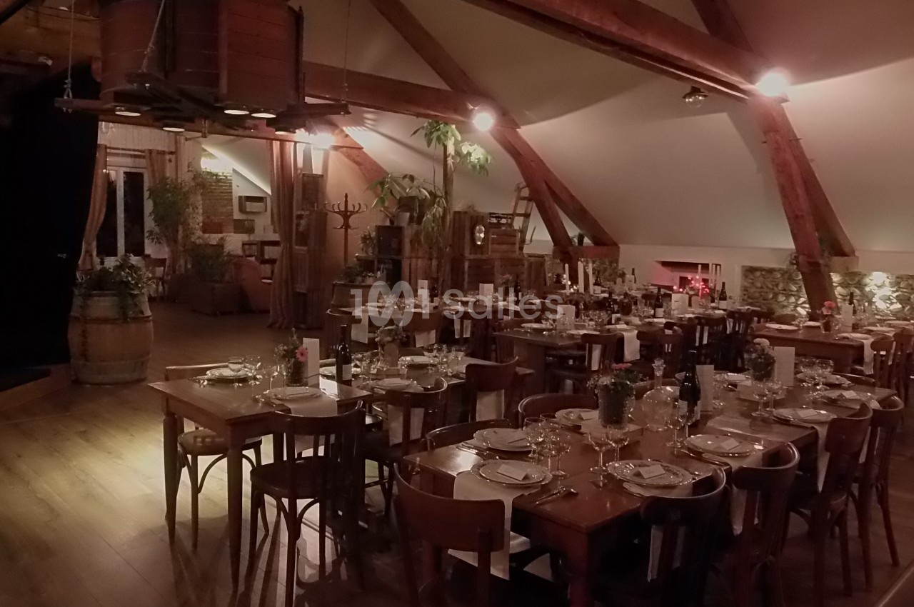 Salle de restaurant rustique avec tables en bois dressées, poutres apparentes et décoration chaleureuse.