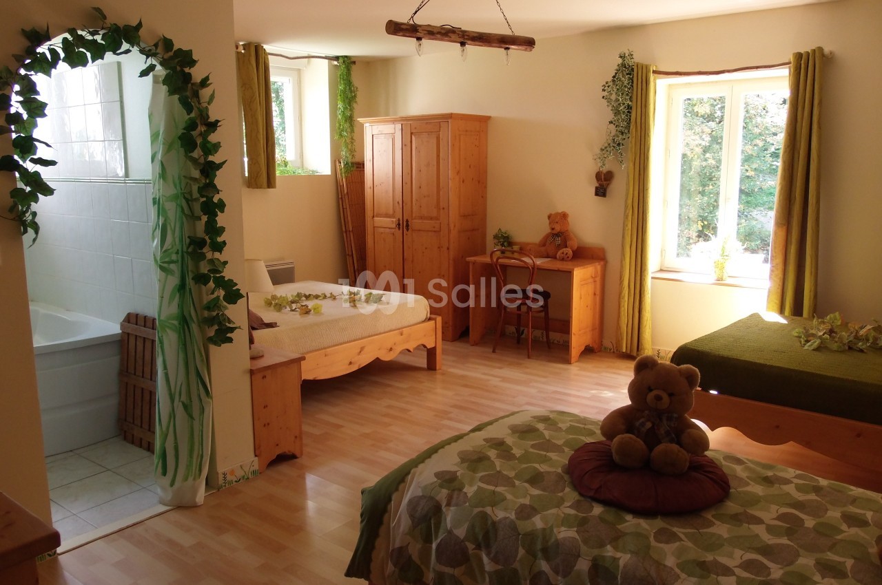 Chambre lumineuse avec lits en bois, bureau, armoire, décorations végétales et vue sur un jardin par la fenêtre.