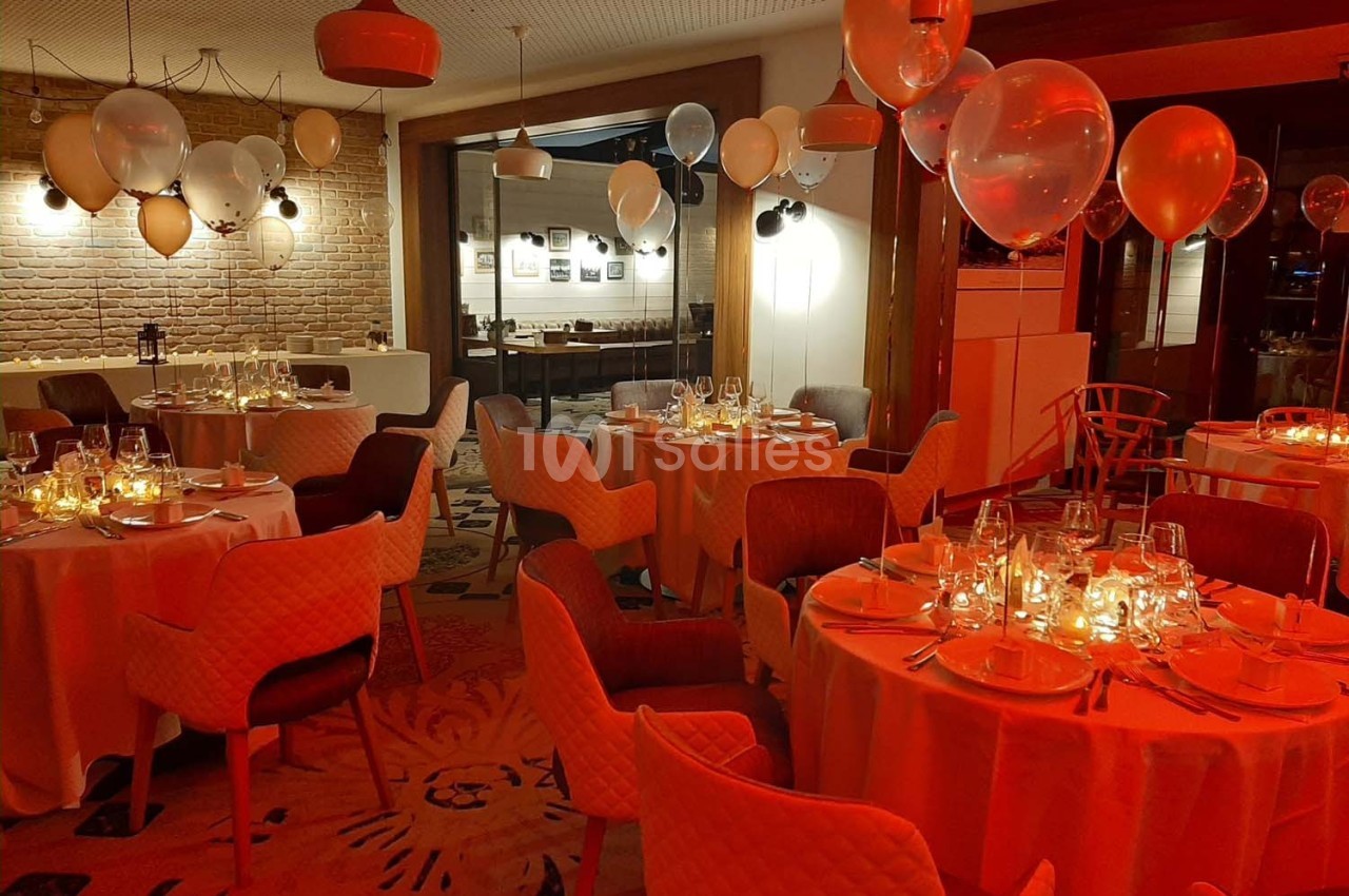 Salle de réception décorée avec des ballons et des tables élégamment dressées sous une lumière tamisée.