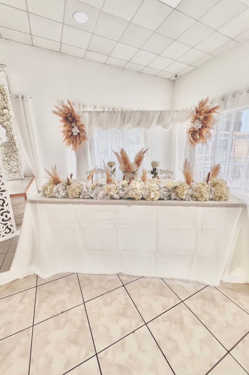 Table décorée avec des fleurs blanches et des ornements de pampas dans une salle lumineuse aux tons neutres.