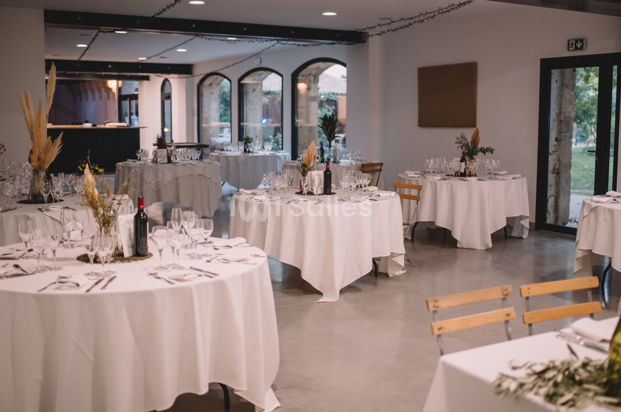 Salle de réception élégamment décorée avec des tables rondes dressées pour un événement.