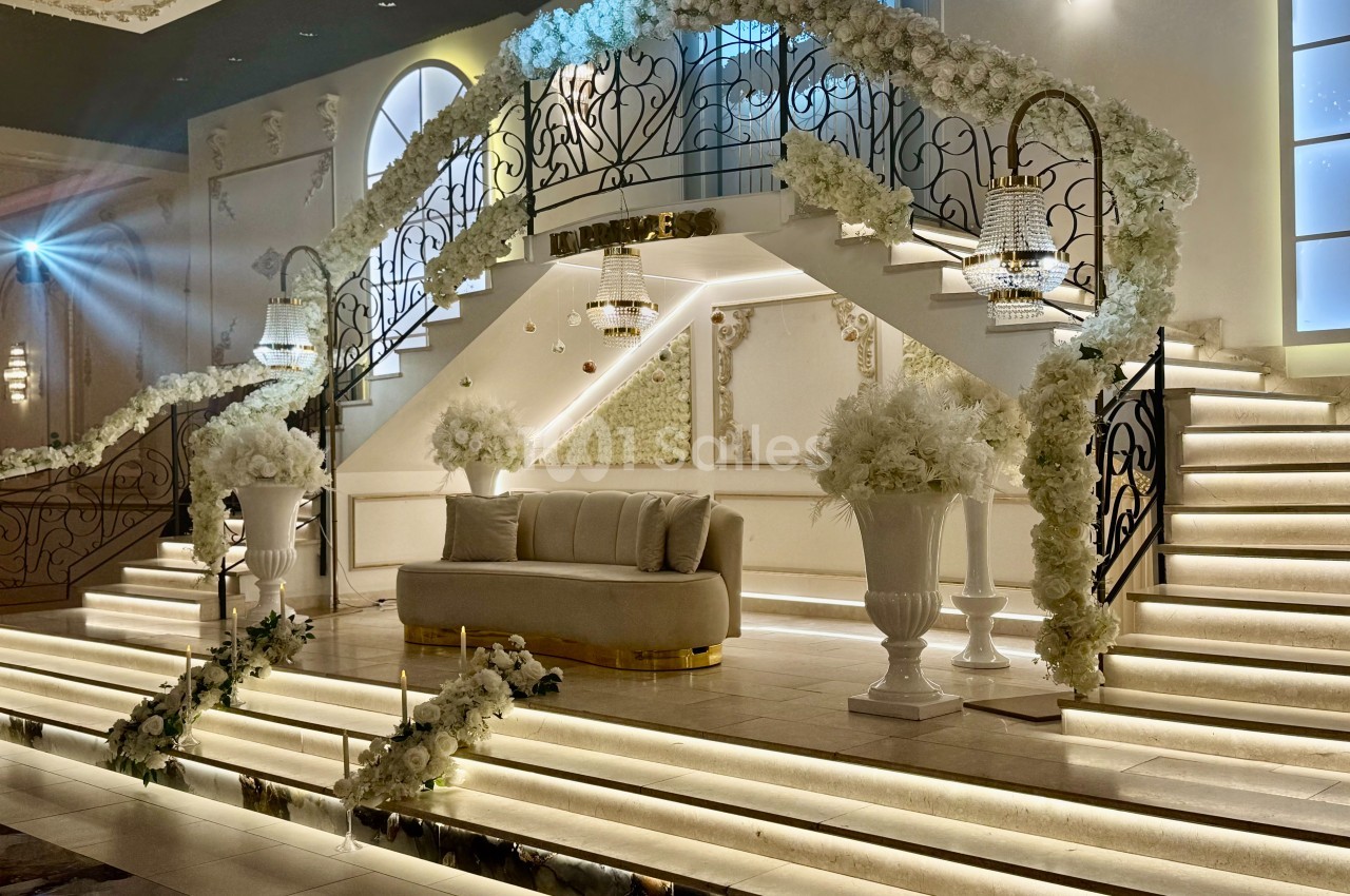 Escalier décoré de fleurs blanches avec un canapé au centre, éclairage chaleureux et ambiance élégante.