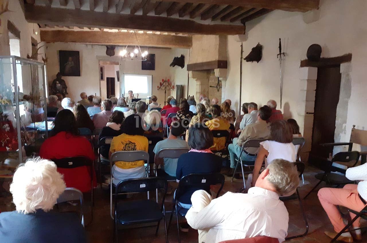 Un groupe de personnes assises dans une salle ancienne assistent à une présentation projetée sur un écran.