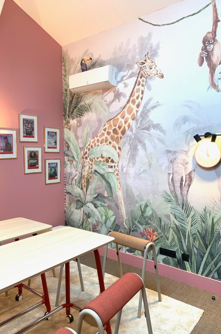 Salle décorée avec des tables, des chaises et une fresque murale représentant des animaux de la savane dans un décor…