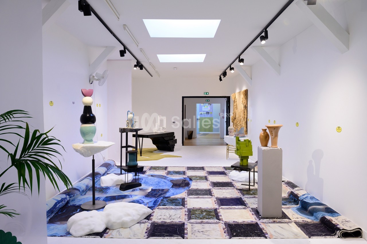 Vue d'une galerie d'art moderne avec sculptures et installations sur un sol à motifs marbrés.