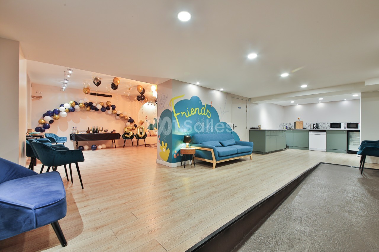 Salle lumineuse avec coin salon, cuisine équipée et décoration festive composée de ballons et d'une arche colorée.