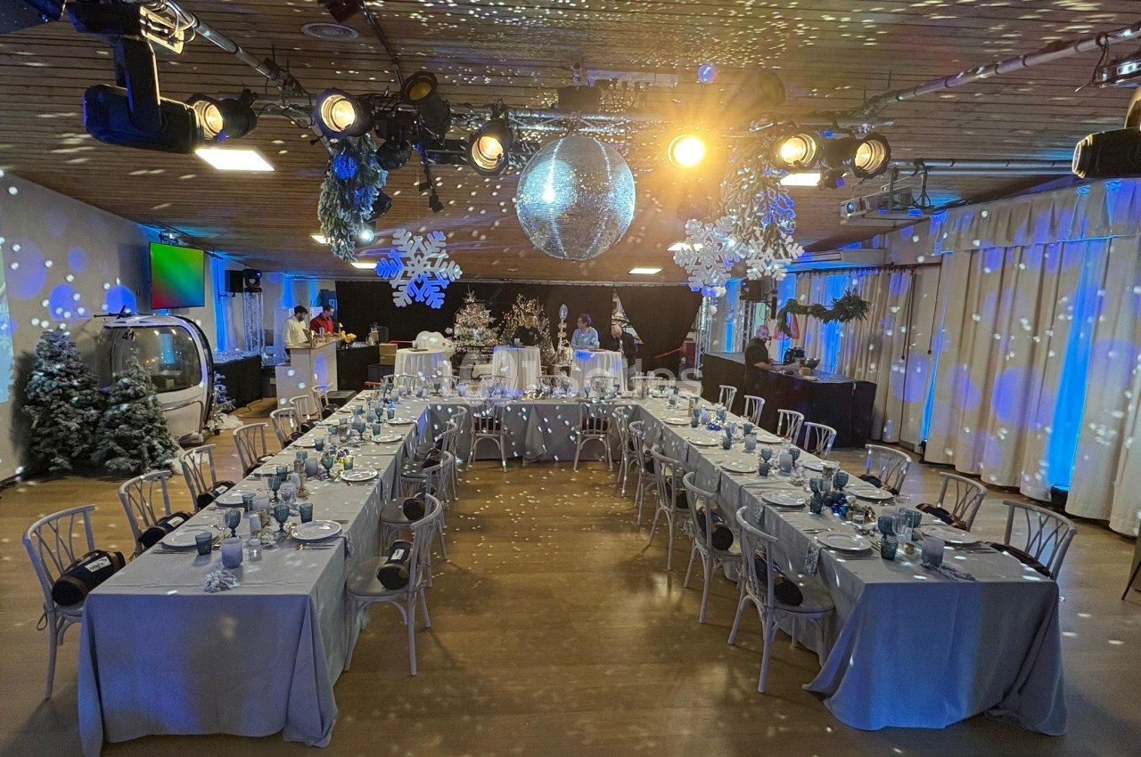 Salle décorée pour un événement festif avec tables dressées en U, éclairage tamisé et boule disco suspendue.