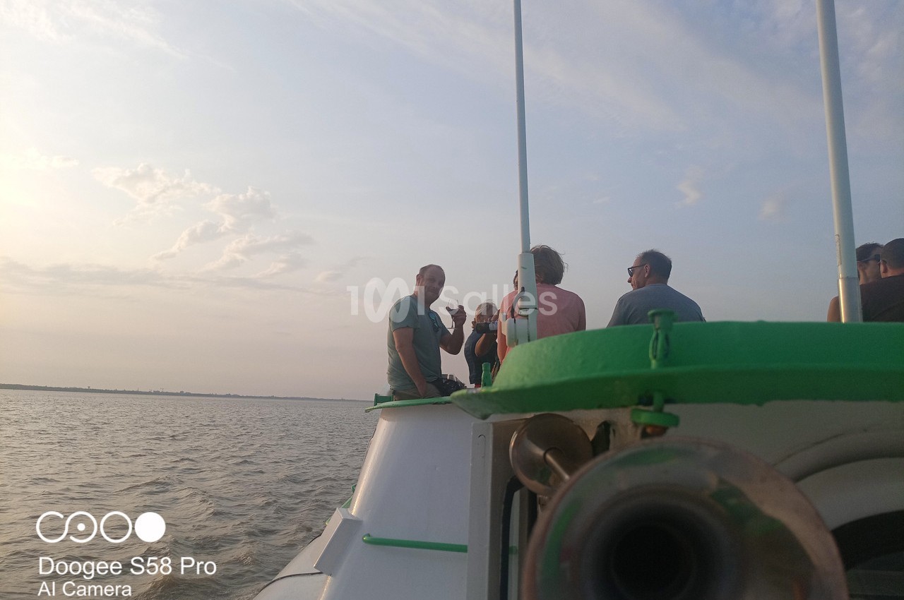 Des personnes discutent sur le pont d'un bateau naviguant sur une étendue d'eau par temps clair.