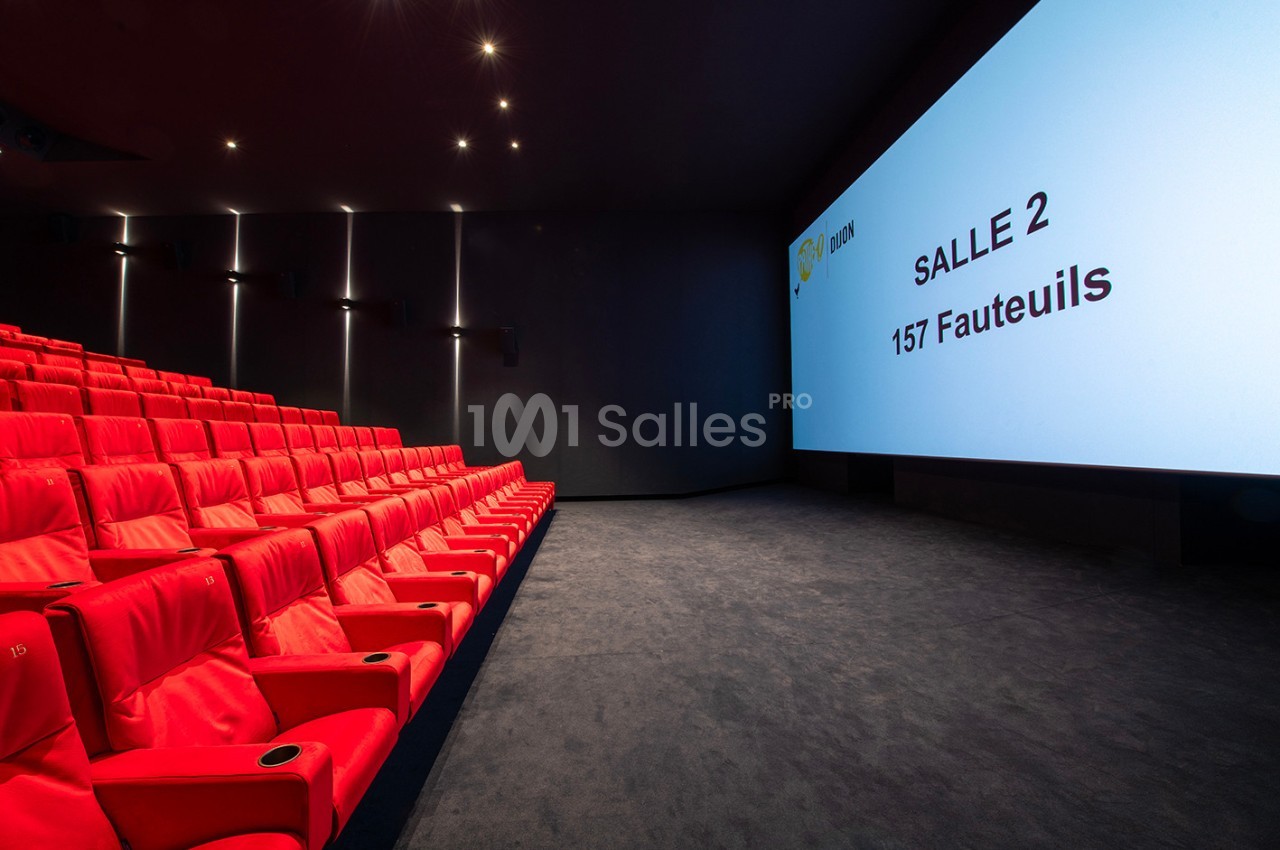 Salle de cinéma moderne avec des sièges rouges alignés et un écran affichant ’Salle 2, 157 fauteuils’.