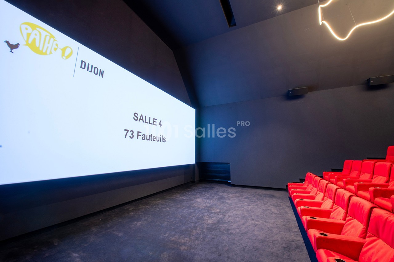 Salle de cinéma moderne avec écran large, sièges rouges et indication ’Salle 4, 73 fauteuils’ sur l'écran.
