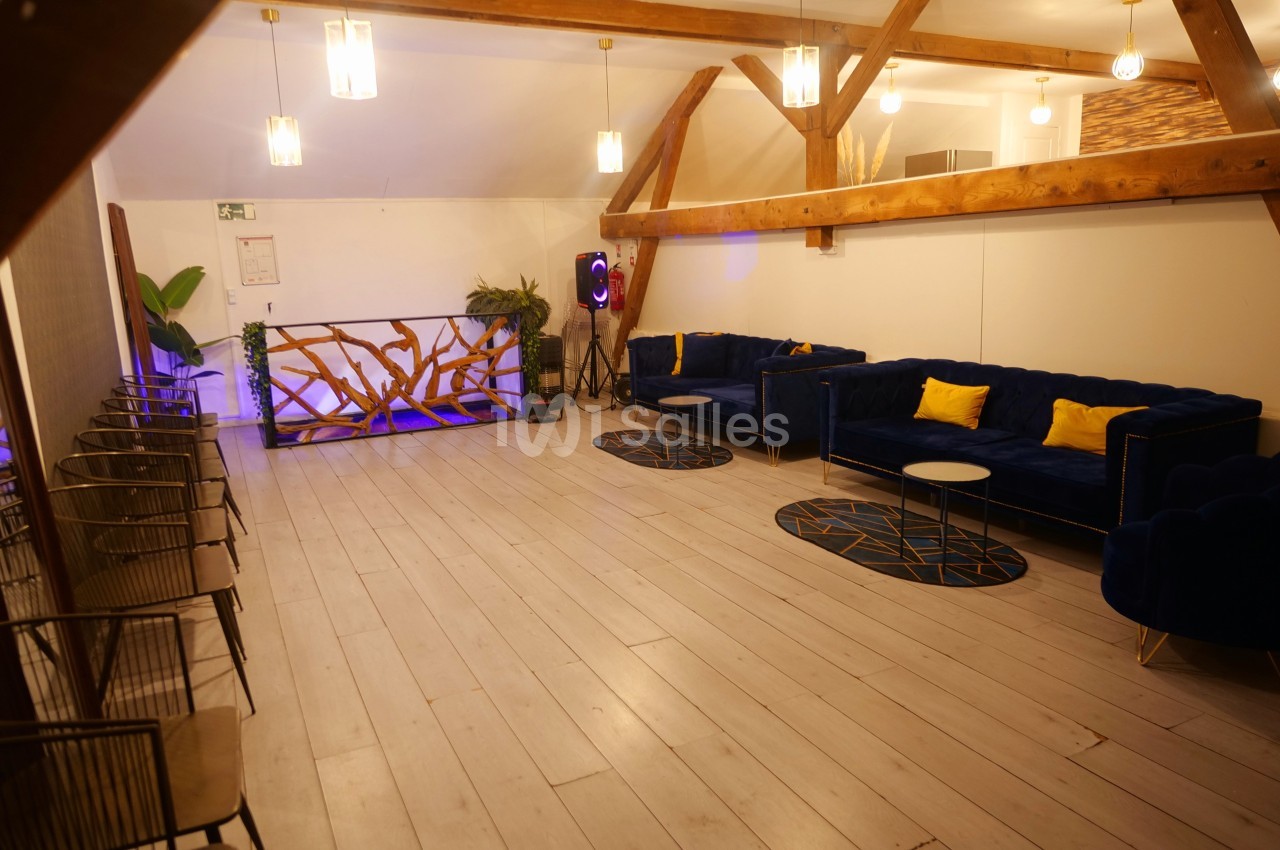 Salle lumineuse avec parquet clair, canapés bleus, coussins jaunes, tables basses et décoration en bois.