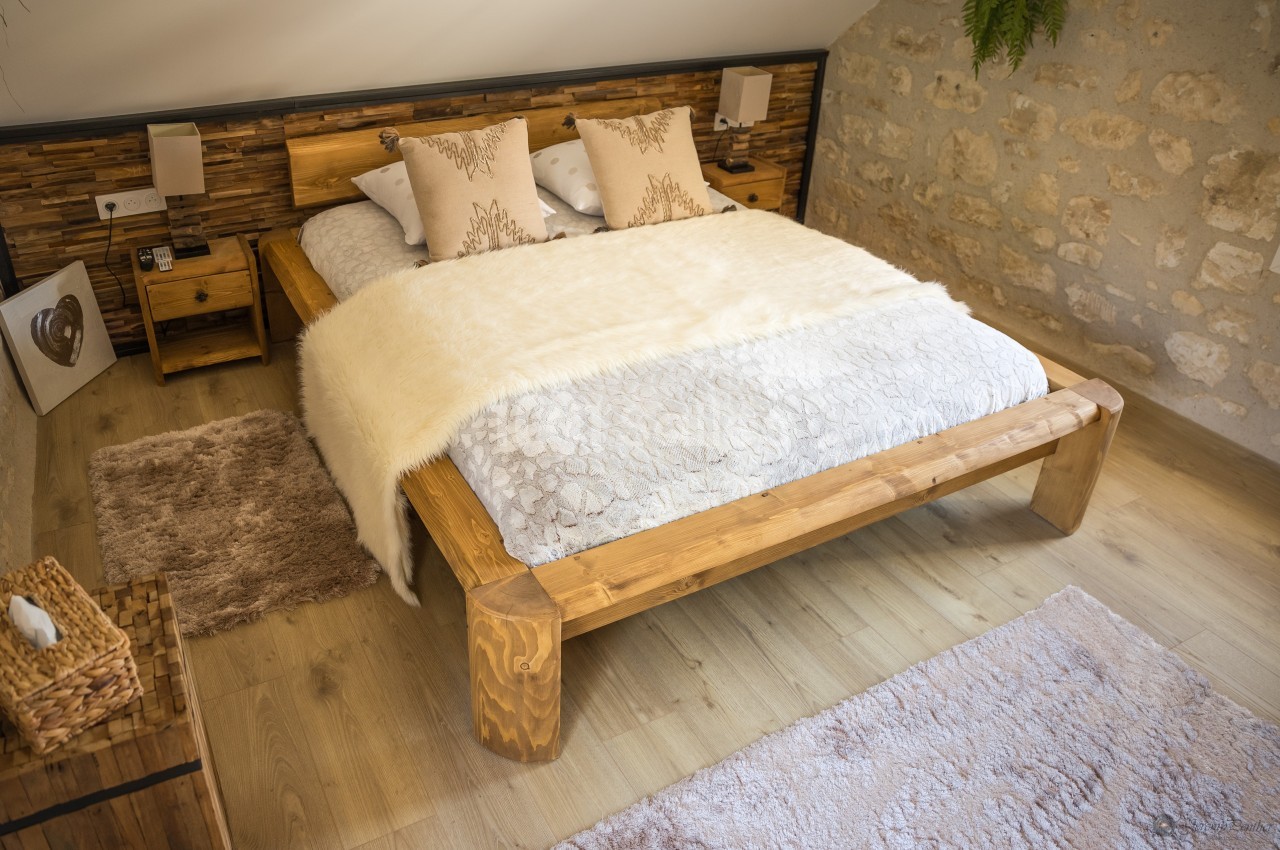 Lit double en bois avec couverture en fausse fourrure, entouré de tables de chevet et décoré dans une chambre aux murs en…