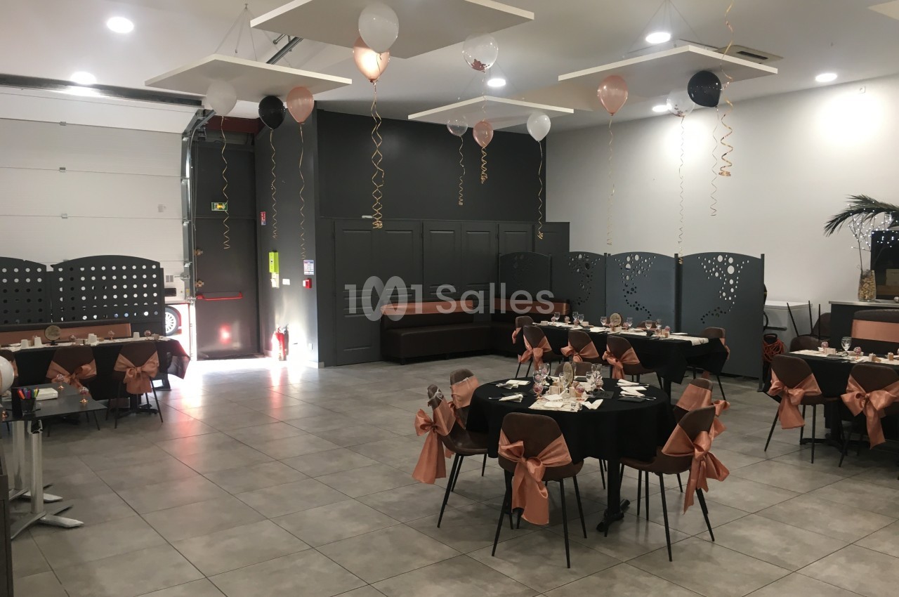 Salle de réception décorée avec des ballons et des tables dressées pour un événement festif.